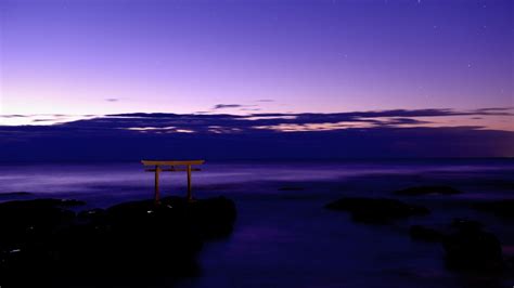 Purple Cloudy Sky Above Body Of Water And Wooden Bench On Rock Hd