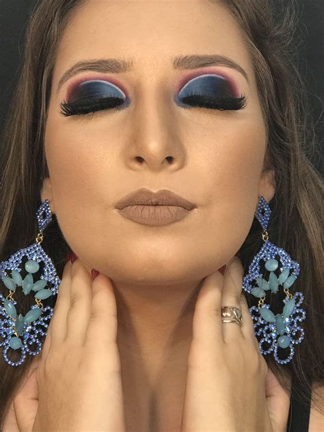 A Woman With Blue Eyeshades And Large Earrings On Her Face Is Posing