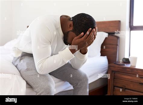Depressed Man Looking Unhappy Sitting On Side Of Bed At Home With Head In Hands Stock Photo Alamy