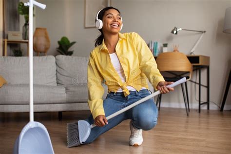 Cheerful African American Woman Having Fun Singing Holding Broom