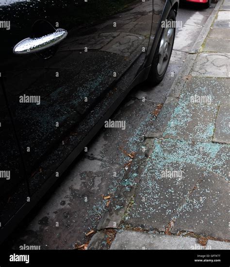 broken glass on the sidewalk pavement beside a car that has been broken into 1st august 2016