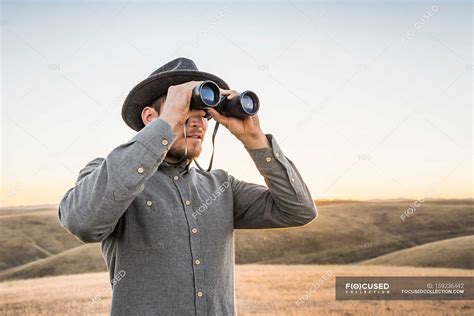 Man Looking Through Binoculars Lifestyle Rolling Landscape Stock Photo