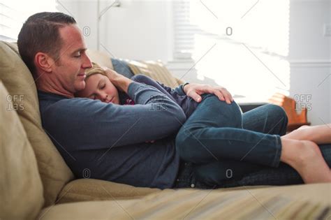 Father Sitting On A Sofa Holding His Sleepy Babe On His Lap Stock Photo OFFSET