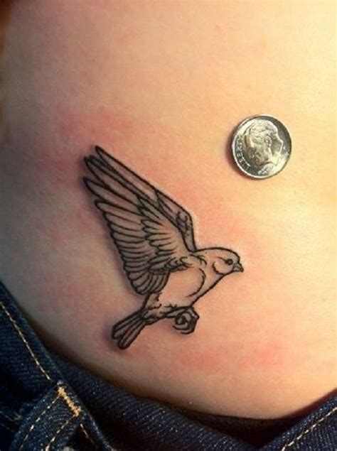 A Small Bird Tattoo On The Side Of A Womans Stomach With A Penny