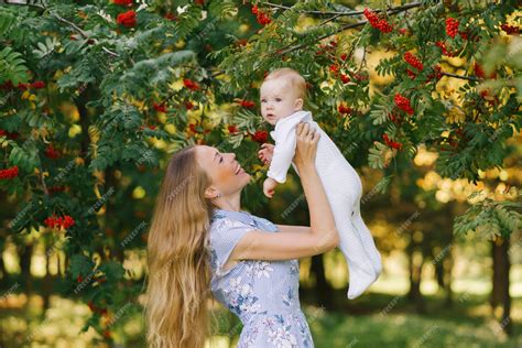 Una Joven Madre Feliz Levanta A Su Pequeño Hijo En Brazos De Un árbol