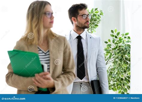 Attractive Young Business Partners Looking Sideways In A Hallway Of