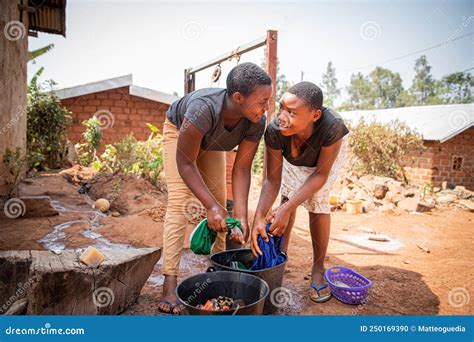 two african girls wash clothes by hand using soap and a bucket traditional life in africa stock