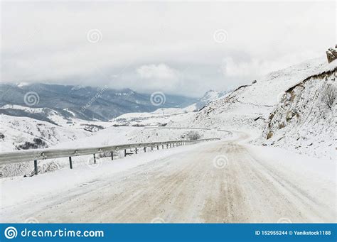 Empty Mountain Asphalt Road In Winter Covered With Snow On A Cloudy Day