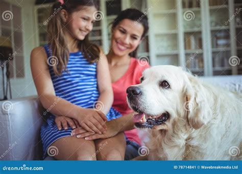 Madre E Hija Que Se Sientan Con El Perro Casero En Sala De Estar Imagen