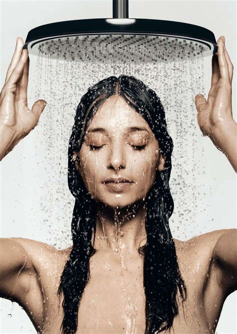 A Woman Standing Under A Shower Head With Her Hands In The Air Above