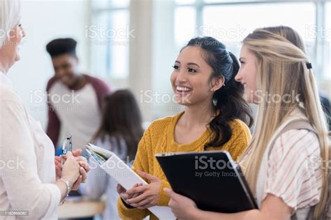Attentive Teenage Girls Talk With Teacher After Class Stock Photo