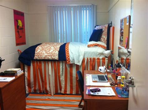Simple College Dorm Room Idea With White Bedding And Orange Stripe Patterned Sleeve And Wooden Desk And Vanity And White Sheer Curtain And White Siding 
