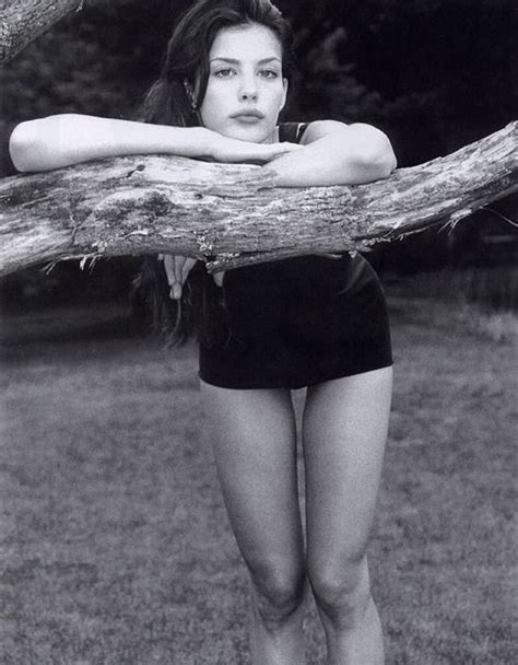 A Black And White Photo Of A Woman Leaning On A Tree Branch