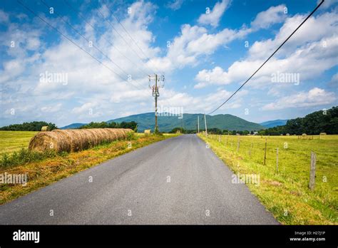 Country Road With Distant Mountains And Farm Fields In The Rural