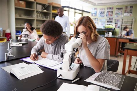 Estudiantes De Secundaria Mirando A Través Del Microscopio En Clase De