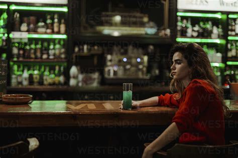 Thoughtful Woman With Drink On Bar Counter Sitting In Restaurant Stock Photo