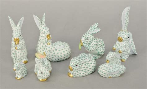 Four White And Green Ceramic Rabbits Sitting Next To Each Other On A
