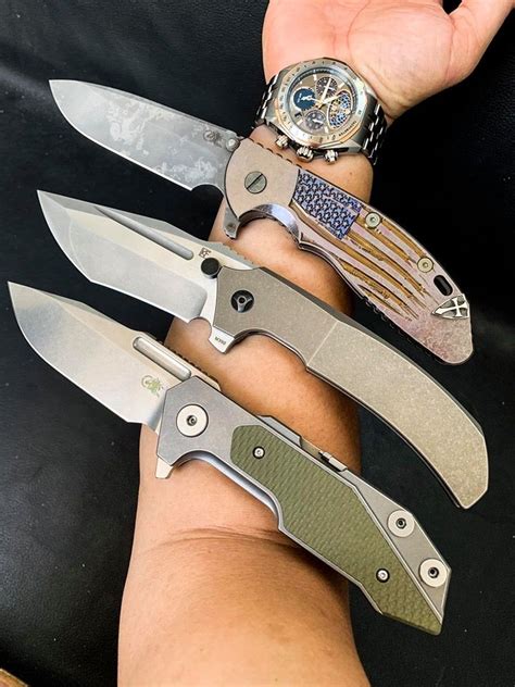 A Persons Hand Holding Several Knives In Different Colors And Sizes On