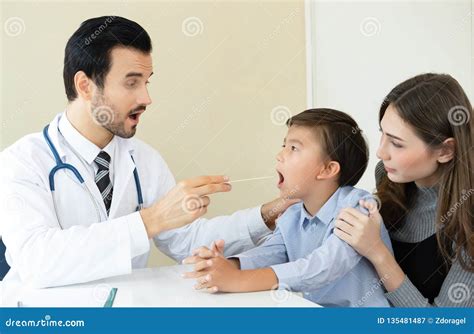 Doctor Measures Checking Throat Of Adorable Little Boy In Clinic