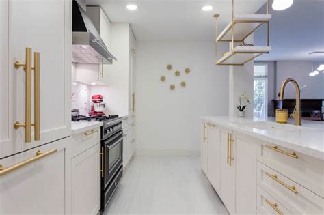 A Kitchen With White Shaker Cabinets And Gold Brass Hardware