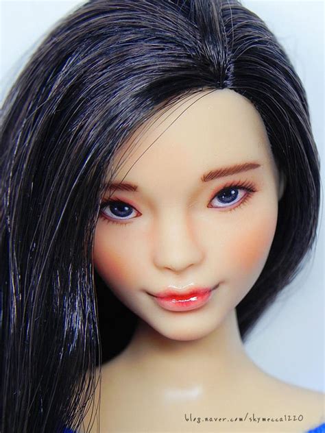 A Close Up Of A Doll With Long Black Hair And Blue Eyes Wearing A Blue