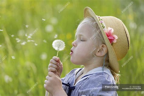 Girl Blowing Dandelion Seeds In Air — Childhood Holding Stock Photo