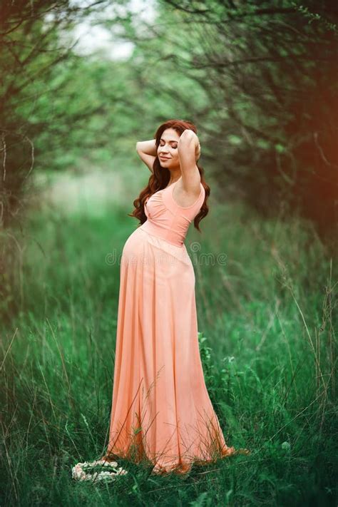 Young Beautiful Pregnant Girl With Long Brown Hair In Peach Dress In