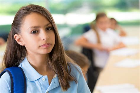 Serious Preteen Girl In Classroom Wearing Private School Uniform Stock