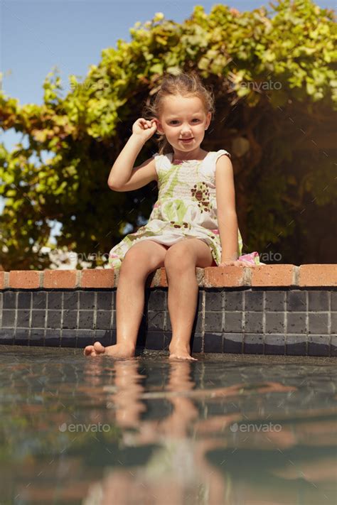 Cute Little Girl Sitting On The Edge Of A Swimming Pool Stock Photo By