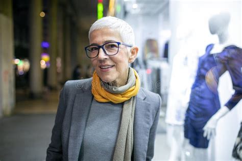 Smiling Mature Senior Woman With Short Gray Hair And Eyeglasses Walking On Street Night Scene