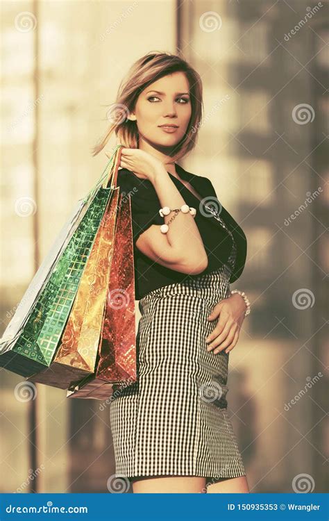 Mulher Nova Feliz Da Forma Com Os Sacos De Compras Na Alameda Imagem De