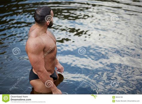 A Muscular Man In Swimming Trunks Looking Into The Distance On The Sea Shore A Swimmer On A