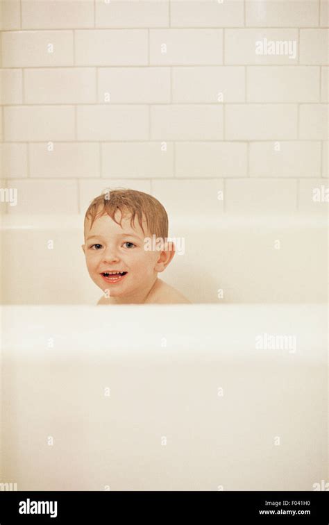 kleiner junge sitzt in der badewanne baden lächelnd in die kamera