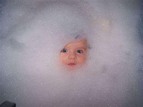 A Baby Is In The Bathtub Surrounded By Bubbles