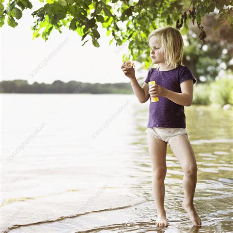 Girl Blowing Bubbles By Lake Stock Image F Science Photo