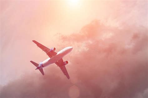 Airplane Flying Above Clouds In Dramatic Sunset Light Stock Photo