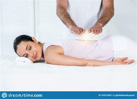 View Of Healer Putting Hands Above Attractive Woman With Closed Eyes Lying On Massage Table