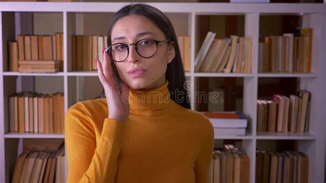 portrait of brunette female teacher in glasses posing into camera and flirting with it at the