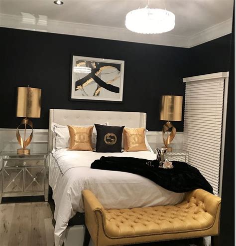 A Bedroom With Black Walls White Bedding And Gold Accents On The Headboard
