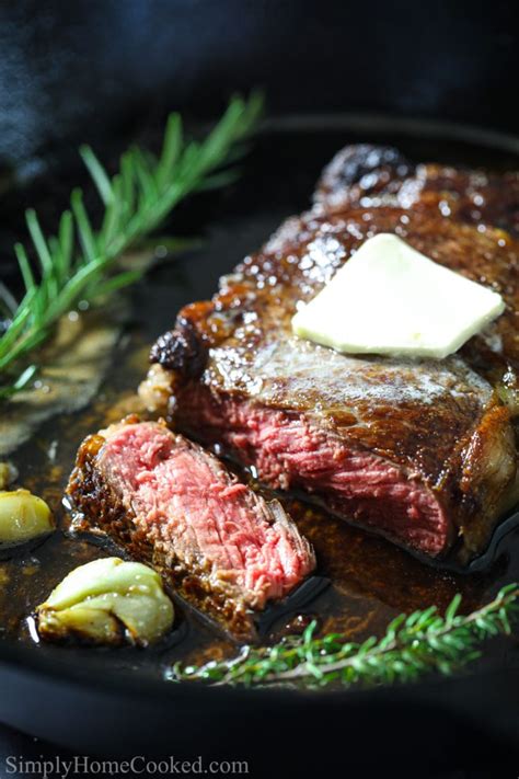 The surface of the steak should be a rich, brown. Ribeye steak sliced on a black platter with butter garlic ...