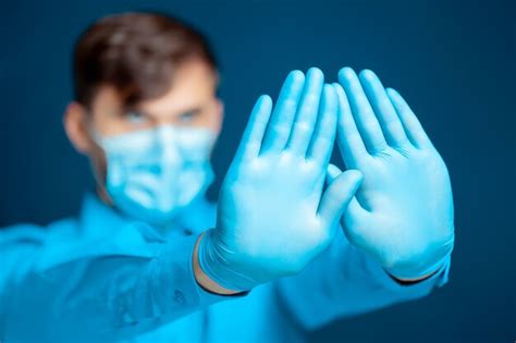 premium photo doctor in a medical mask and gloves in a blue uniform put his hands in front of