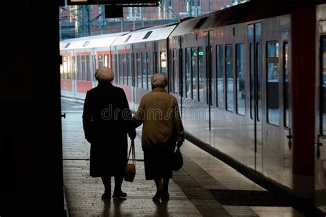 two elderly women attend the train station along the train view from the back editorial stock