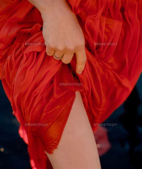 A Woman Lifts Her Red Wet Dress And Exposes Her Legs 11100132043 の写真素材