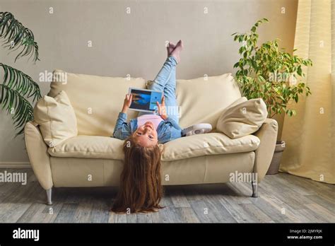 Little Girl Lying Upside Down On Sofa Stock Photo Alamy