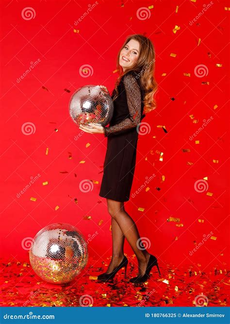 brunette girl is standing in a black dress holding a disco ball in her hands flying golden