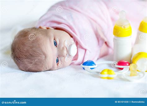 Cute Newborn Baby Girl With Nursing Bottles And Pacifier Stock Photo