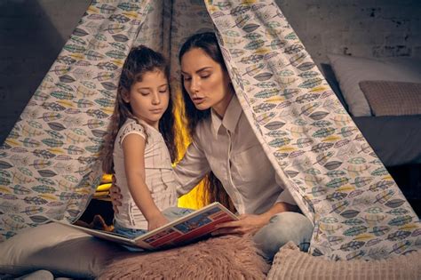 Premium Photo Mother And Daughter Are Sitting In A Teepee Tent With Some Pillows And Reading