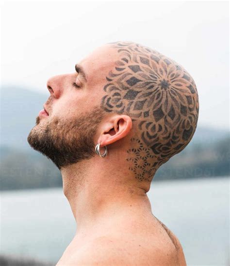 Side View Of Tranquil Male With Tattooed Bald Head Standing With Closed