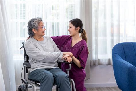 caregiver nurse take care a senior patient sit on wheelchair nurse helping senior woman stock