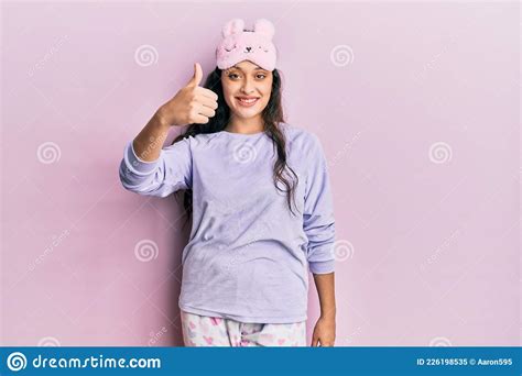 beautiful middle eastern woman wearing sleep mask and pajama smiling happy and positive thumb